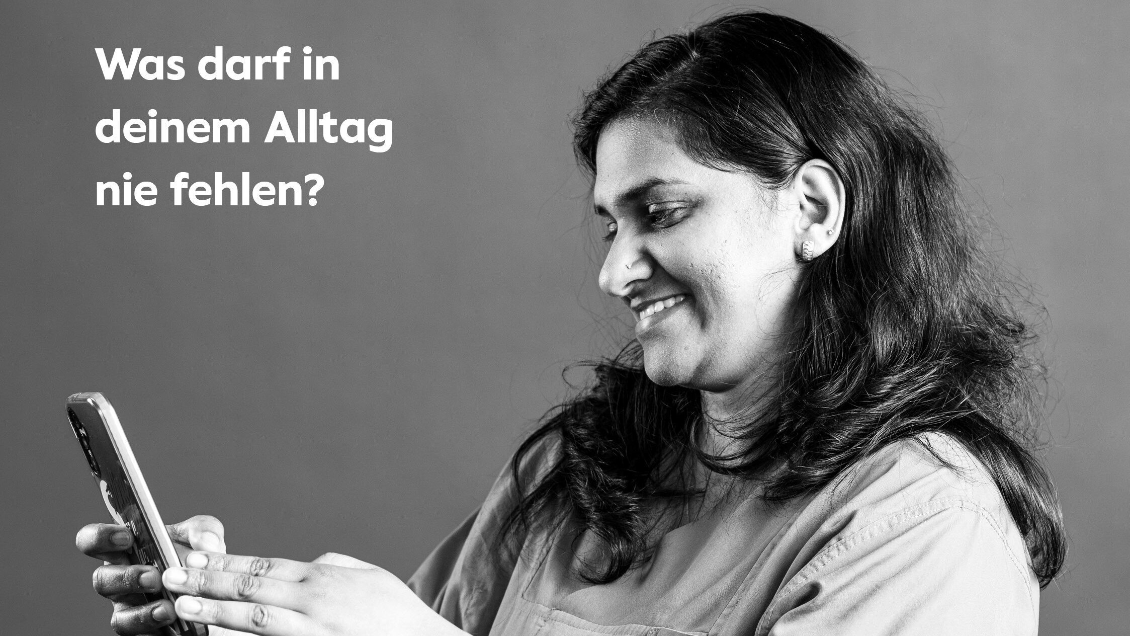 Das Foto der Serie "Sag jetzt nichts" zeigt die Pflegekraft Merin Rajan aus Indien mit der Frage "Was darf in deinem Alltag nicht fehlen?", die ein Handy in der Hand hält.