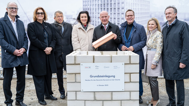 Die Grundsteinlegung für den Neubau des Deutschen Herz-Zentrums der Charité fand am 6. Oktober 2025 statt. Mehrere Personen stehen um einen Mauerstein mit einer Tafel, die Informationen zum Projekt enthält. Einer der Anwesenden hält eine Kupferkapsel.